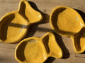 Three yellow ceramic bowls with 'Bennett' and 'Faulk' branding on a wooden surface.